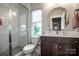 Well-lit bathroom features a glass-enclosed shower, a vanity with storage and a round mirror at 13708 Huntson Park Ln, Huntersville, NC 28078