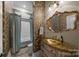 Elegant bathroom with a decorative mirror, designer wallpaper, and a shower-tub combination at 1629 Southpoint Ln, New London, NC 28127