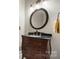 Bathroom vanity with dark wood cabinet, black countertop, and round mirror at 179 Browning Dr, Taylorsville, NC 28681