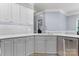 Updated kitchen with a stainless steel dishwasher, faucet, grey lower cabinets, white upper cabinets and tile backsplash at 179 Browning Dr, Taylorsville, NC 28681