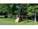 Close up view of a wooden playset featuring a slide, swings, and climbing structure in backyard at 179 Browning Dr, Taylorsville, NC 28681