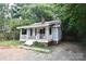 Quaint bungalow featuring a covered front porch and brick foundation, surrounded by mature trees at 2017 Ashley Rd, Charlotte, NC 28208