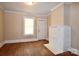 Cozy room featuring a painted brick fireplace, hardwood floors, neutral paint, and a door at 2017 Ashley Rd, Charlotte, NC 28208
