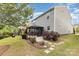 Spacious backyard featuring lush grass, a covered patio, beautiful landscaping, and a charming fire pit area at 2037 Christopher Wood Ct, Fort Mill, SC 29707