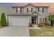 Two-story home featuring neutral siding, black shutters, a two-car garage and manicured landscaping at 2037 Christopher Wood Ct, Fort Mill, SC 29707