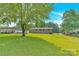Expansive backyard with lush green grass, mature trees, and partial view of brick home and outbuildings at 2323 Brookwood Rd, Lincolnton, NC 28092