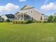 Back exterior view of the home showcasing the screened-in porch, large yard, and manicured shrubs at 3007 Arsdale Rd, Waxhaw, NC 28173