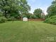 Spacious backyard with green lawn, mature trees, wood fence and storage shed at 3408 Oak Tree Trl, Matthews, NC 28105