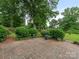 A backyard patio with brick pavers, lush landscaping, mature trees, and a grassy area beyond at 3408 Oak Tree Trl, Matthews, NC 28105