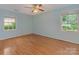 Light and airy bedroom featuring hardwood floors, two windows, and light-blue walls at 3408 Oak Tree Trl, Matthews, NC 28105