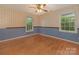 Bedroom with hardwood floors, two windows, a ceiling fan, and wallpaper accents at 3408 Oak Tree Trl, Matthews, NC 28105
