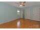 A light blue bedroom with hardwood floors, a ceiling fan, and a view into the attached bathroom at 3408 Oak Tree Trl, Matthews, NC 28105