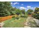 Landscaped backyard with wooden fence, lush lawn, stone walkway, and a variety of trees and plants at 5424 Tilley Manor Dr, Matthews, NC 28105