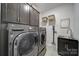 Well-equipped laundry room with modern washer, dryer, sink, storage cabinets, and tile flooring at 5424 Tilley Manor Dr, Matthews, NC 28105