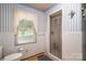 The bathroom features white tile, a walk-in shower, a toilet, and a window at 5958 Hoover Elmore Rd, Lincolnton, NC 28092