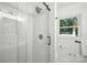 Modern bathroom featuring a glass shower door, marble tiling, and bright window at 6127 Eagle Peak Dr, Charlotte, NC 28214