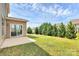 Backyard featuring a concrete patio, sliding door, and a border of privacy trees at 10004 Perth Moor Rd, Charlotte, NC 28278