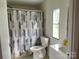 Bright bathroom featuring a toilet, shower with geometric curtain, and vanity with a window providing natural light at 1201 Forest Ridge Rd, Bessemer City, NC 28016