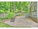 Private brick patio and backyard featuring lush lawn and wooded area and a rustic fire pit at 14203 Queens Carriage Pl, Charlotte, NC 28278