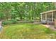 Lush backyard with manicured lawn, wooded area, patio, and screened porch at 14203 Queens Carriage Pl, Charlotte, NC 28278