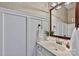 Well-lit half bathroom with a vanity, decorative mirror, and stylish wall paneling at 14203 Queens Carriage Pl, Charlotte, NC 28278