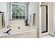 Soaking tub and glass shower, bathed in natural light from the large window overlooking lush greenery at 14203 Queens Carriage Pl, Charlotte, NC 28278