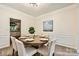 Elegant dining room with a modern light fixture, wall paneling, and seating for six at 14203 Queens Carriage Pl, Charlotte, NC 28278
