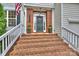 Inviting brick front porch with stairs, decorative plants, and a classic black front door at 14203 Queens Carriage Pl, Charlotte, NC 28278