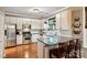 Bright kitchen features white cabinets, stainless steel appliances, granite counters and a breakfast bar with wooden stools at 14203 Queens Carriage Pl, Charlotte, NC 28278