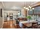 Open kitchen and dining area featuring stainless steel appliances, white cabinets, hardwood floors and pendant lighting at 14203 Queens Carriage Pl, Charlotte, NC 28278