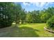 Expansive backyard with lush green grass, mature trees, and a tree line at 15116 Legend Oaks Ct, Fort Mill, SC 29707