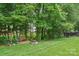 Enjoy this spacious backyard that offers a seating area with a stone firepit surrounded by mature trees at 1575 Williamsburg Dr, Rock Hill, SC 29732