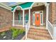 Inviting front porch with brick steps, white railings, and a vibrant orange front door at 1575 Williamsburg Dr, Rock Hill, SC 29732