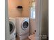 Bright laundry room featuring a front loading washer and dryer, storage shelf and sunny window with valance at 1575 Williamsburg Dr, Rock Hill, SC 29732