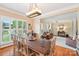 Bright dining room with wood table, chairs, and view of landscaped yard through plantation shutters at 207 Spaniel Se Dr, Concord, NC 28025