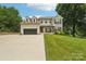 Charming brick home featuring dormer windows, attached garage, inviting front porch, and manicured lawn at 207 Spaniel Se Dr, Concord, NC 28025