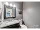 Stylish half bathroom with granite countertop, elegant mirror, and gray walls at 207 Spaniel Se Dr, Concord, NC 28025