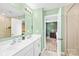 Bathroom featuring dual sinks, white cabinets, a large mirror, and a tiled floor at 2717 Aubrey St, Monroe, NC 28110
