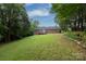 Spacious backyard with a grassy lawn and mature trees and a brick home in the background at 328 Burrage Ne Rd, Concord, NC 28025