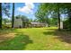 Large backyard with green grass, mature trees and additional buildings at 336 Oakwood Dr, Mount Holly, NC 28120