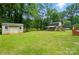 Spacious backyard with green grass, a shed, and a charming barn-style building at 336 Oakwood Dr, Mount Holly, NC 28120