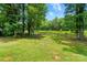 Lush backyard view with green grass, mature trees, and a charming wooden fence at 336 Oakwood Dr, Mount Holly, NC 28120