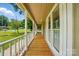 Long front porch with wood floors, white railing, and large windows overlooking the yard at 336 Oakwood Dr, Mount Holly, NC 28120