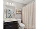 Well-lit bathroom featuring a dark vanity, a neutral shower curtain, and decorative shelving at 417 Livingston Dr, Lancaster, SC 29720