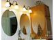 Bright bathroom featuring three decorative mirrors, updated lighting fixtures, and classic wooden cabinetry at 4492 Antelope Ln, Charlotte, NC 28269