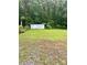 The backyard features a storage building and a spacious grassy area surrounded by trees at 5022 Wrenn Dr, Denver, NC 28037