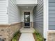 Close-up of the front door with black trim and sidelights, brick foundation, and gray siding at 507 Webster Ln, Cramerton, NC 28032
