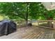 Relaxing back deck area with a grill and table, perfect for outdoor entertaining surrounded by mature trees at 6313 Weddington Rd, Concord, NC 28027