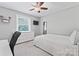 This bedroom has a light gray color scheme, a ceiling fan, and a large window for natural light at 6313 Weddington Rd, Concord, NC 28027