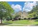 Side view of a two-story home with yellow siding, a well-manicured lawn, mature trees, and blue sky at 8044 Hawk Crest Ct, Charlotte, NC 28270